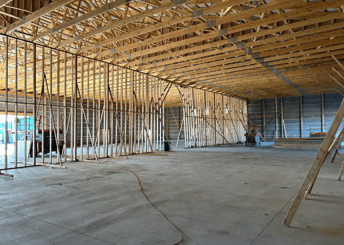 Interior of a commercial building under construction with wooden framing and exposed trusses.