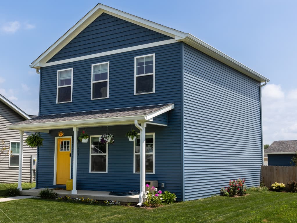 Two-story home with blue vinyl siding, white trim, and covered front porch built by C-U Under Construction in Champaign, IL