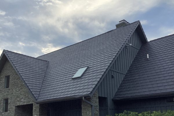 Stone home with new dark gray roof shingles and skylight installation