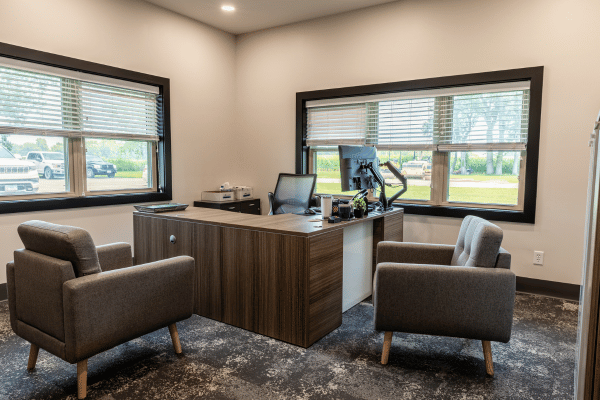 Finished commercial office space with wood desk, guest chairs, and large windows