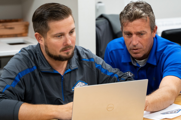 Two C-U Under Construction team members reviewing a project on a laptop