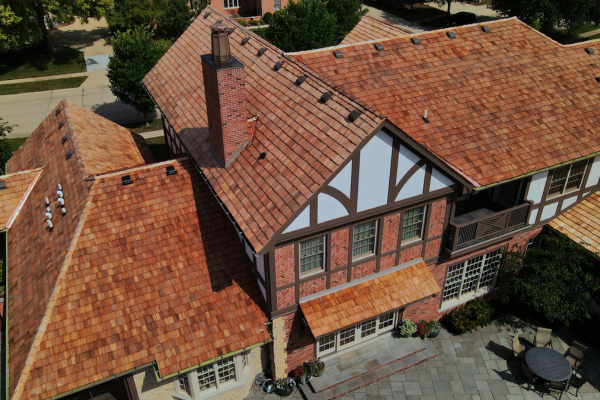 Aerial view of a Tudor style home with cedar shake roof and brick exterior